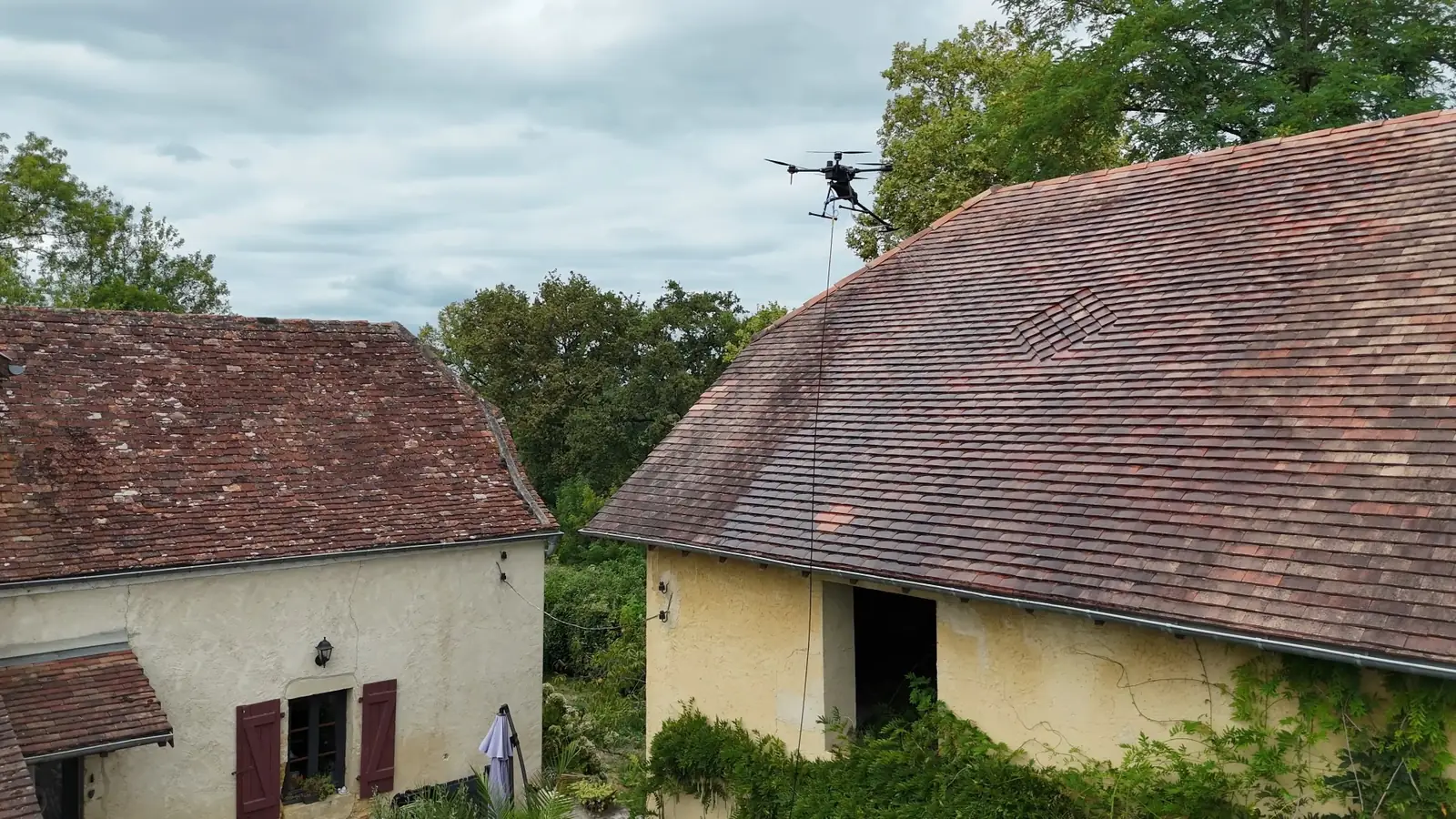 Drone de pulvérisation HBC Drone Solutions traitant la toiture en tuiles d'une maison béarnaise, près de Pau